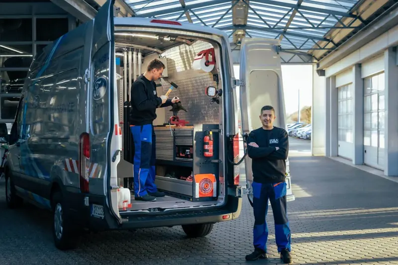 R&S Servicemobil mit geöffneten Hecktüren und zwei Mitarbeitern